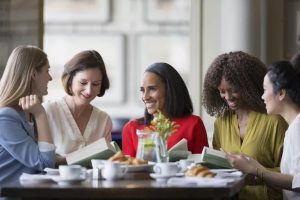 women-friends-discussing-book-club-book-at-restaurant
